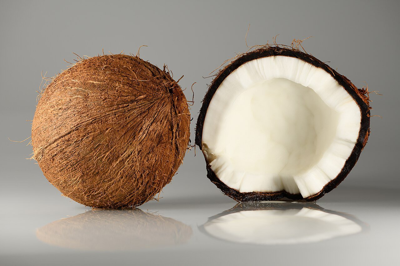 Coco inteiro e cortado ao meio mostrando a polpa branca